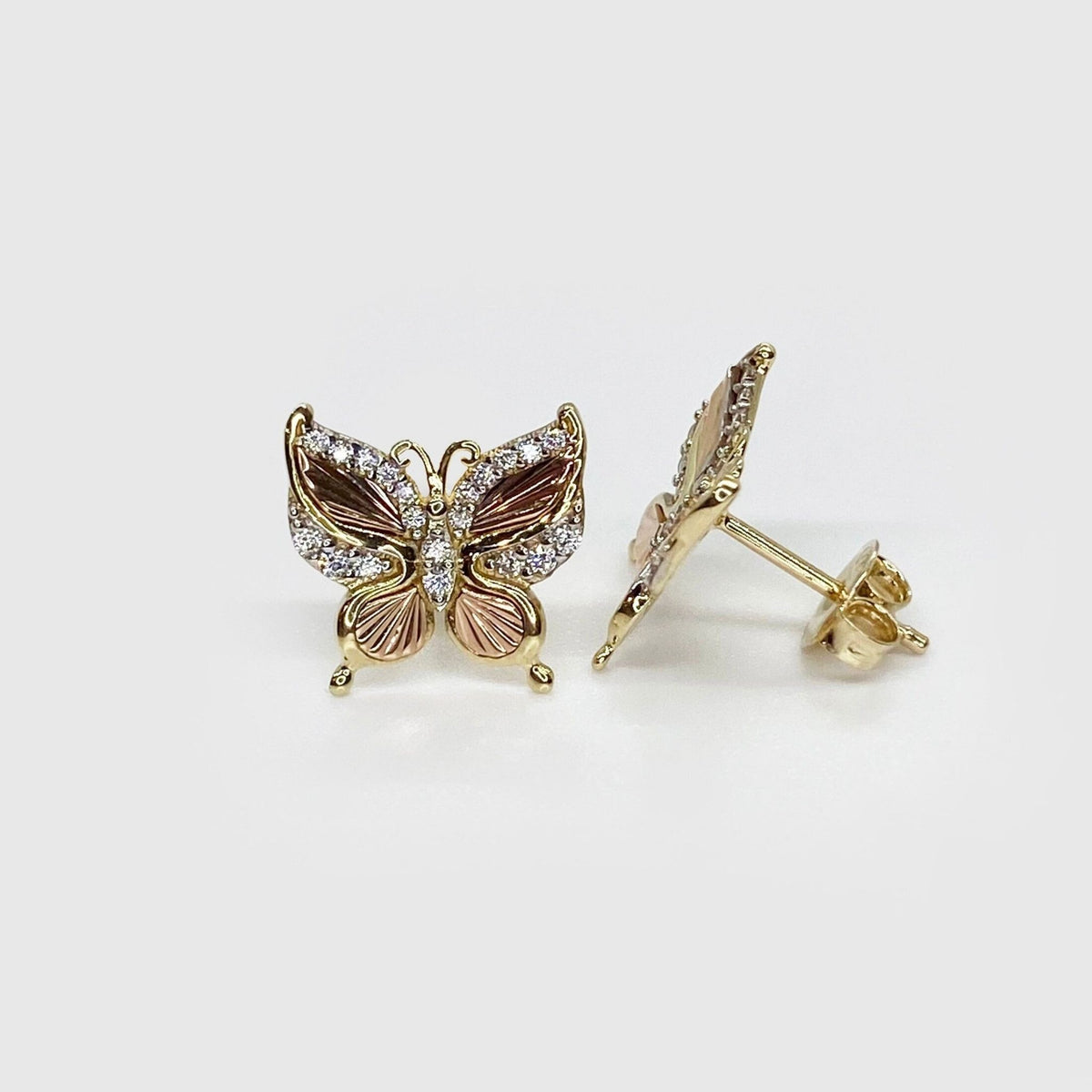 Front and profile view of gold and rose gold butterfly stud earrings with stones.