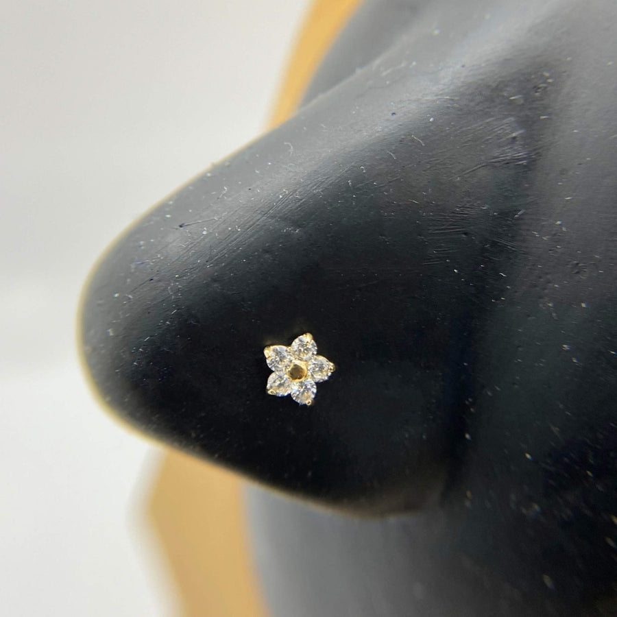 Close-up of a 14k gold floral CZ ball end nose ring on a mannequin.