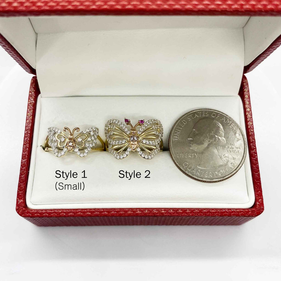 Two 14k gold butterfly shaped earrings in a red box with a quarter for scale.