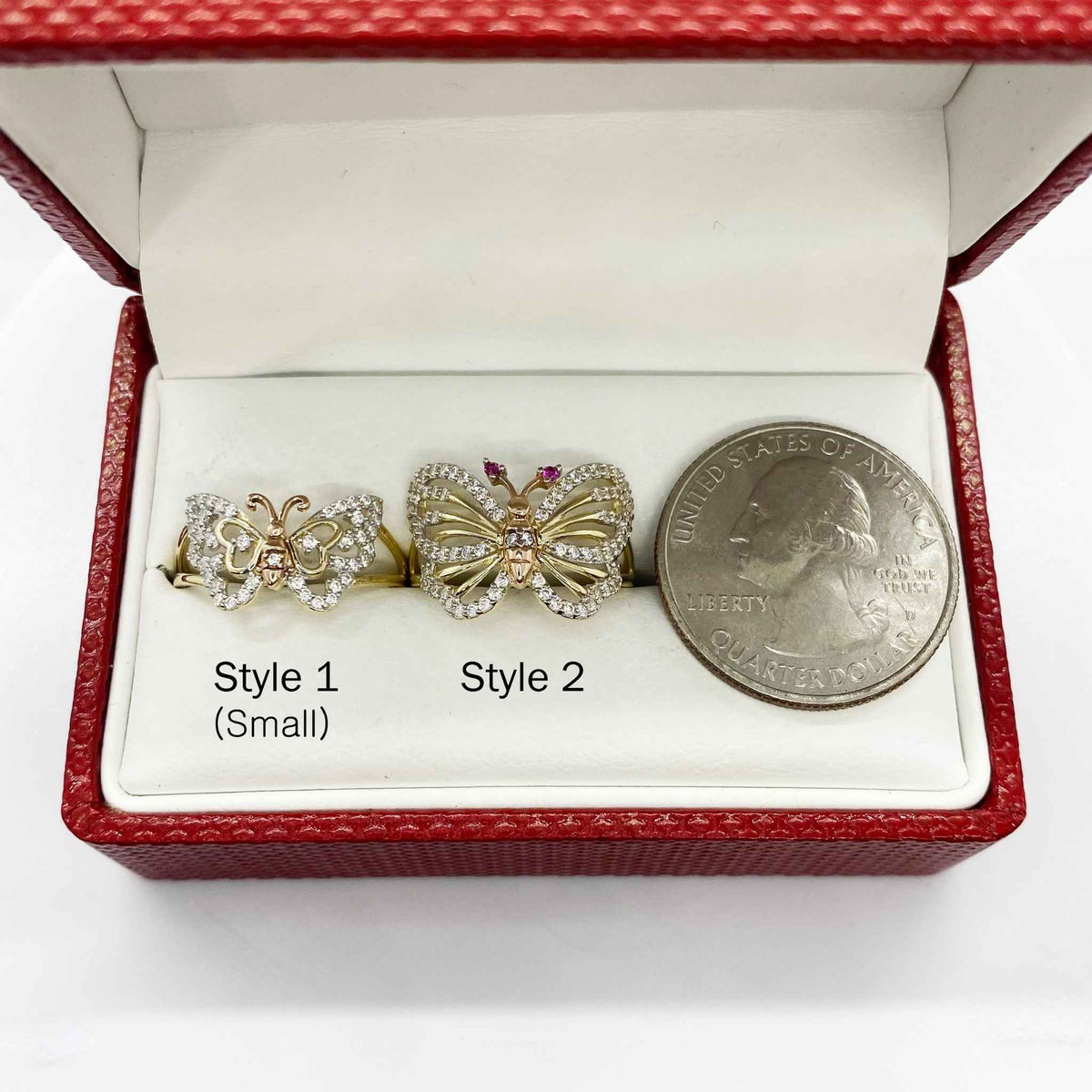 Two 14k gold butterfly shaped earrings in a red box with a quarter for scale.