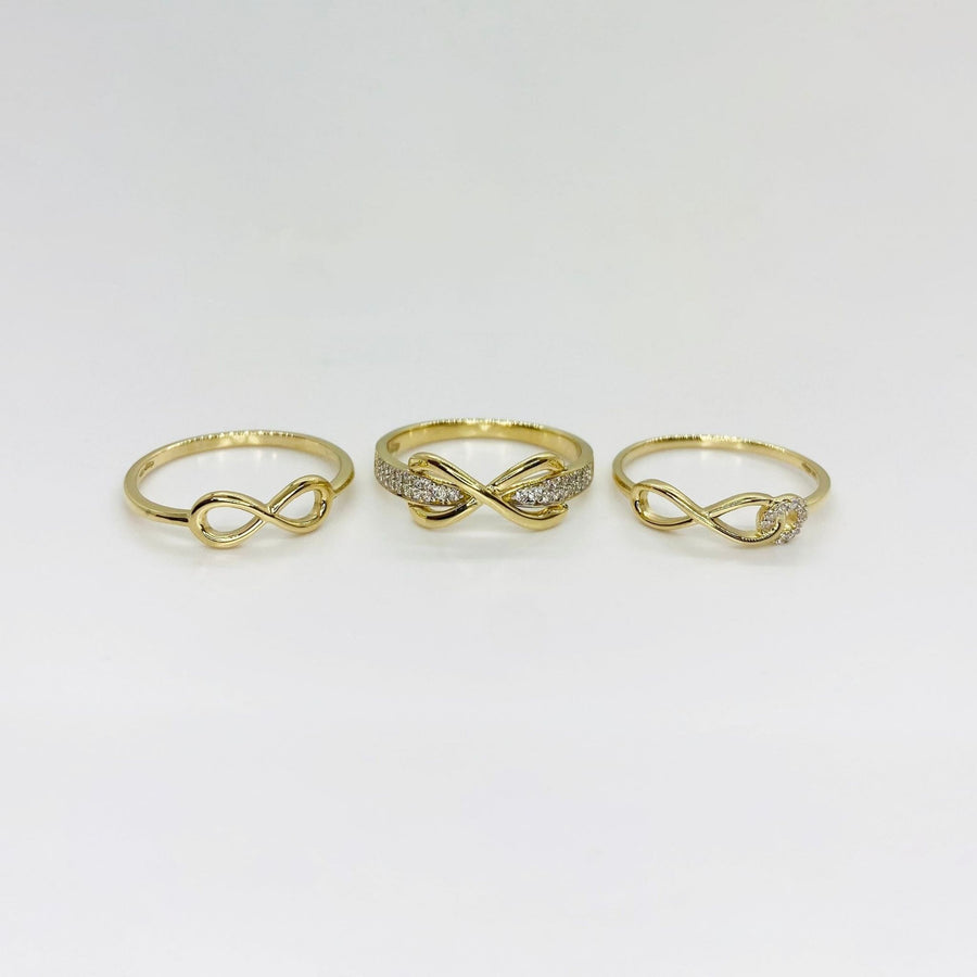 Three 14k gold rings with different infinity designs on a light gray background