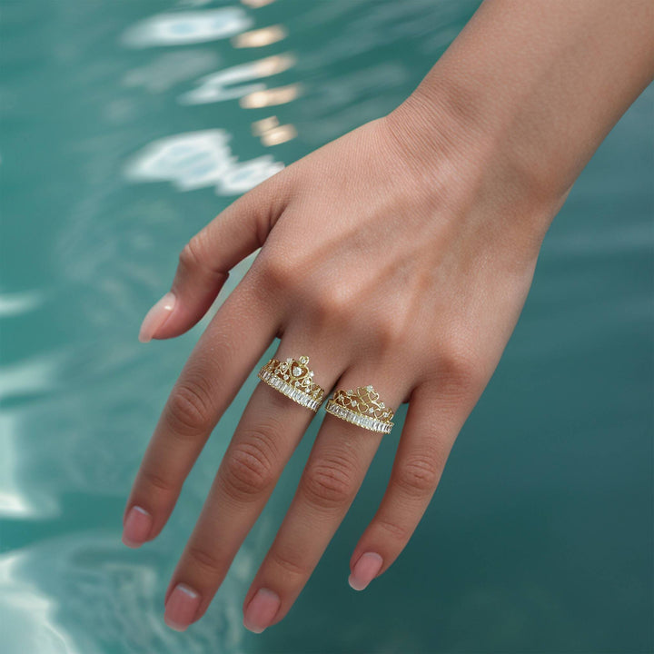 Lifestyle view of 14k gold Lisa crown cubic zirconia rings near shimmering water.