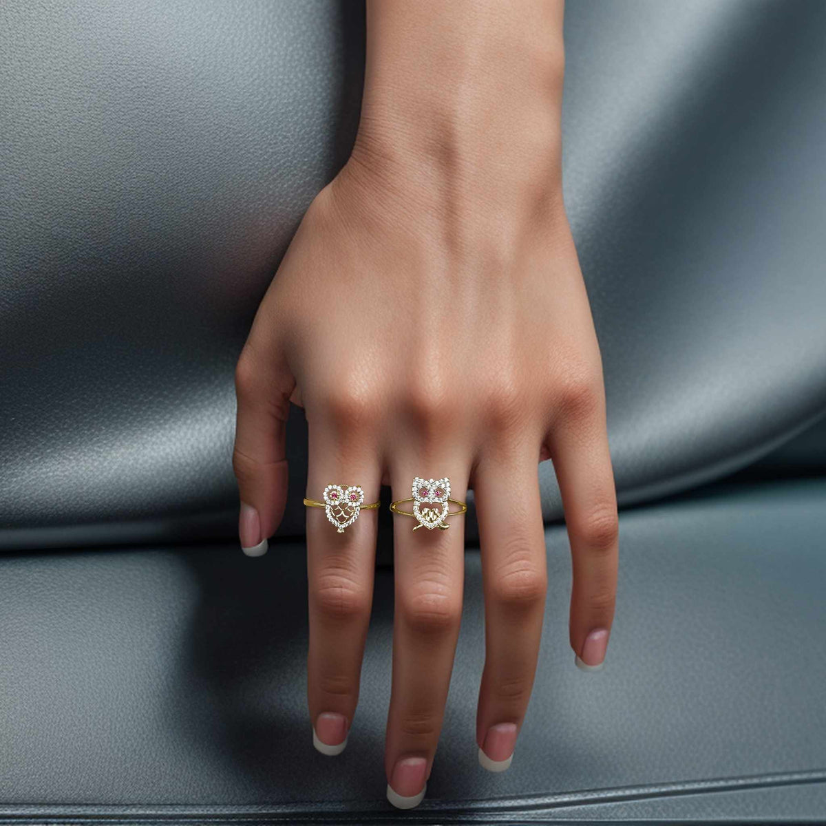 Model wearing a two-tone gold owl crystal ring on a hand against a grey surface.