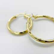Pair of 14k gold 2mm matte diamond cut hoop earrings for a sophisticated look.
