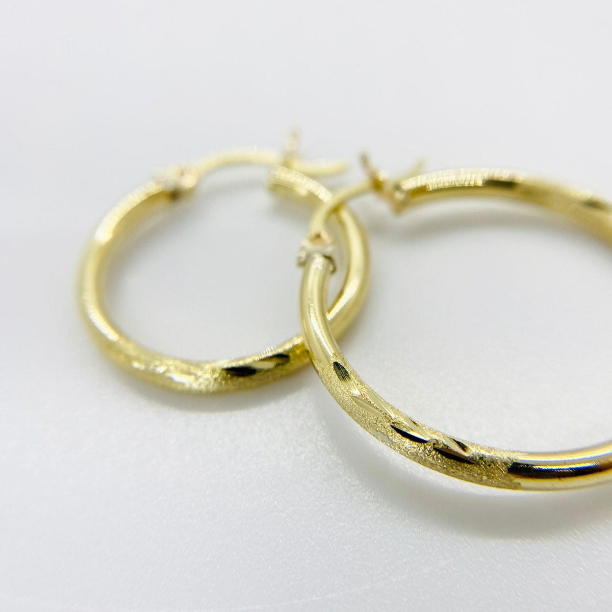 Pair of 14k gold 2mm matte diamond cut hoop earrings for a sophisticated look.