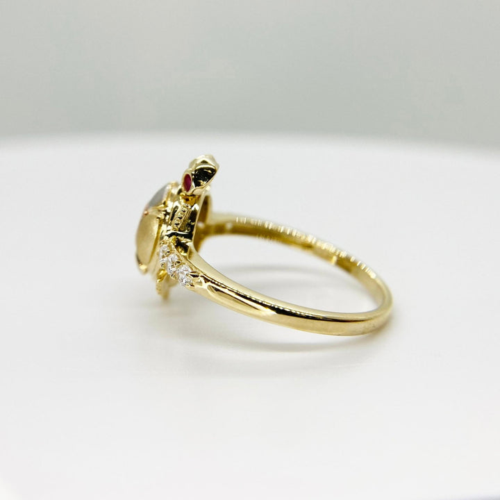 14k Gold ring with a mini turtle design side view on a light gray background