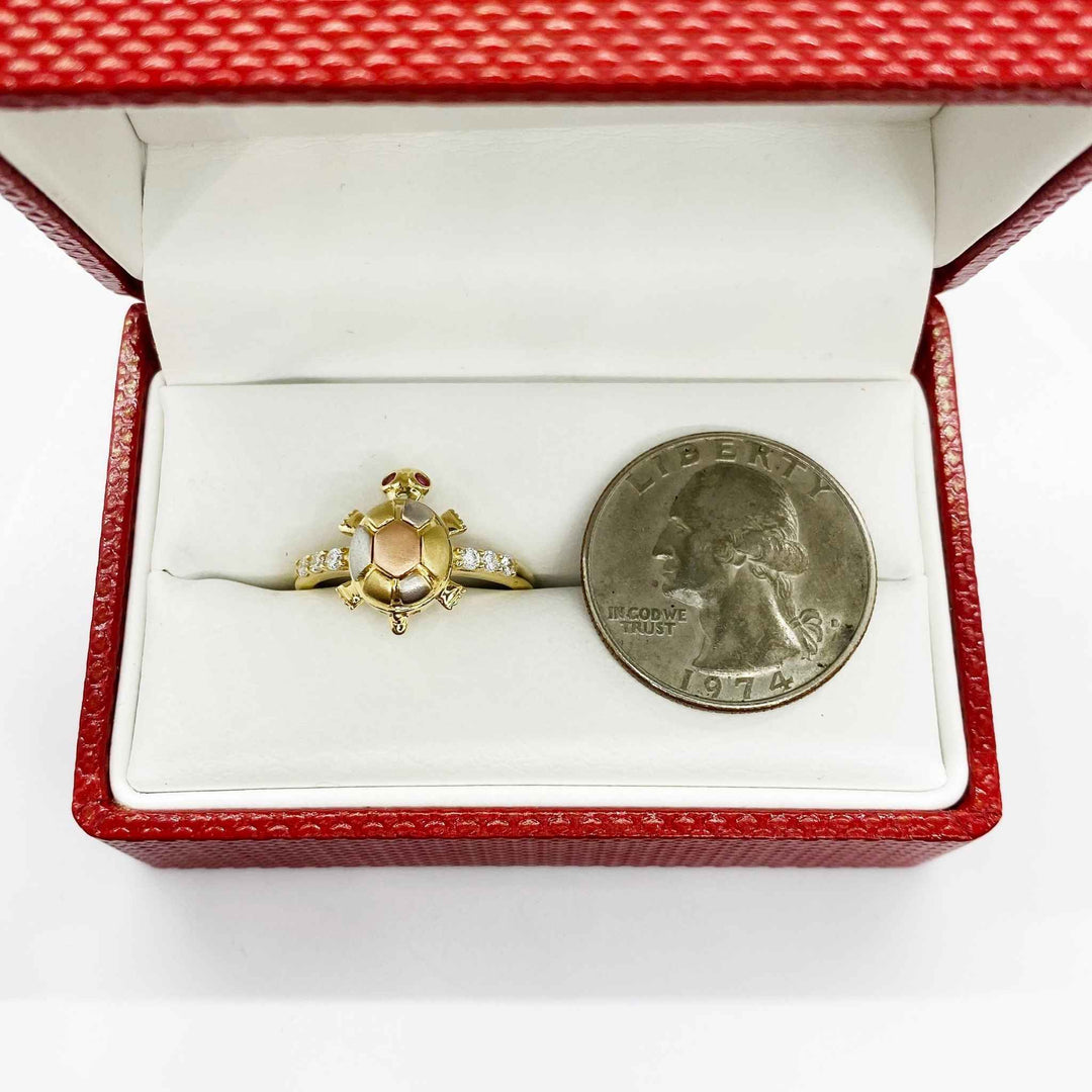 14k Gold ring with a turtle design in a red jewelry box next to a quarter for scale.