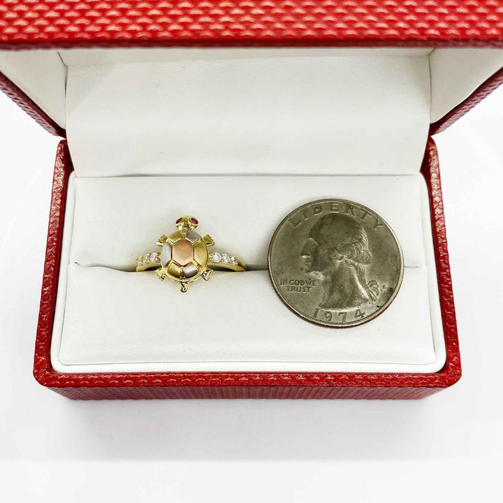 14k Gold ring with a turtle design in a red jewelry box next to a quarter for scale.