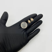 Pair of gold turtle earrings with red eyes held by a black-gloved hand next to a quarter.