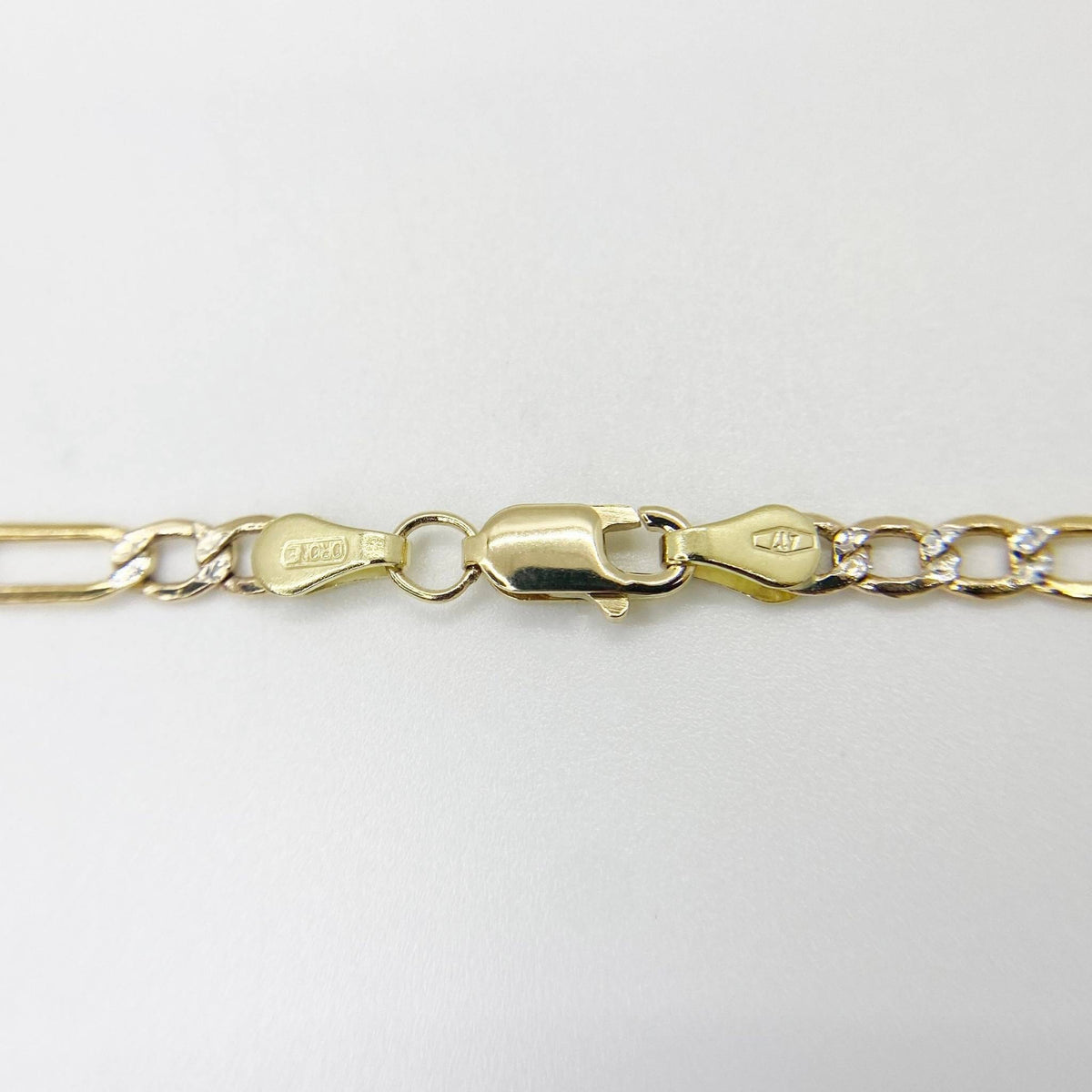 Detailed shot of a 14k gold pavé Figaro chain highlighting the lobster clasp closure.