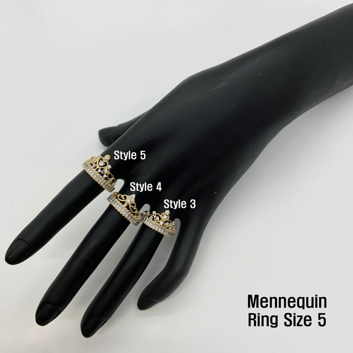 Black mannequin hand wearing three 14k gold crown rings with three different styles