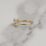 Side view of a 14k yellow gold butterfly ring resting on white marble.