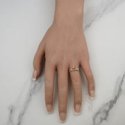 Top-down view of a 14k gold butterfly ring worn over white marble.