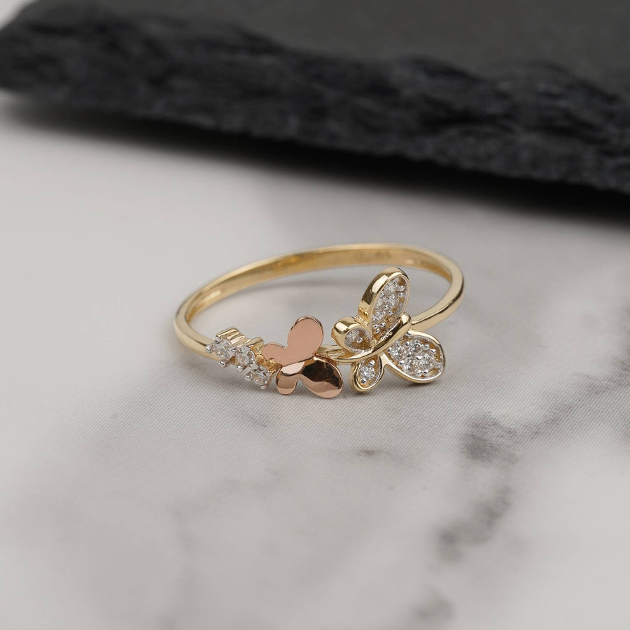 Dainty two-tone 14k gold butterfly ring with cubic zirconia on white marble.