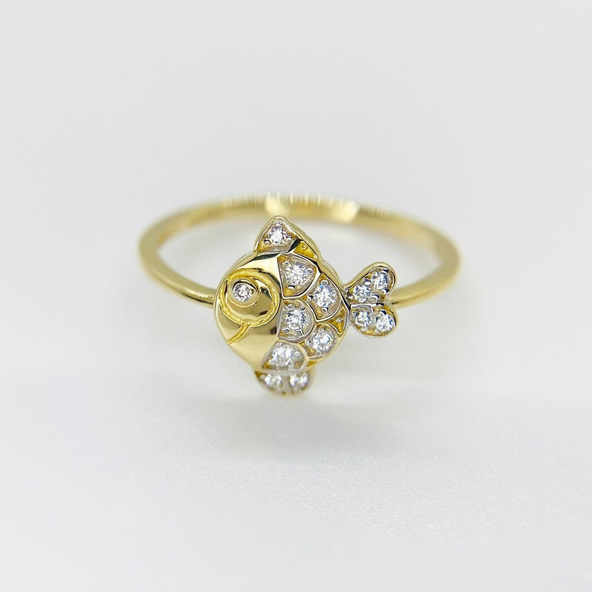 14k Gold ring with fish and sparkling cubic zirconia design on a light gray background
