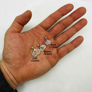 Small, Medium, and Large 14k gold Virgin Mary crown pendants shown in an open hand.