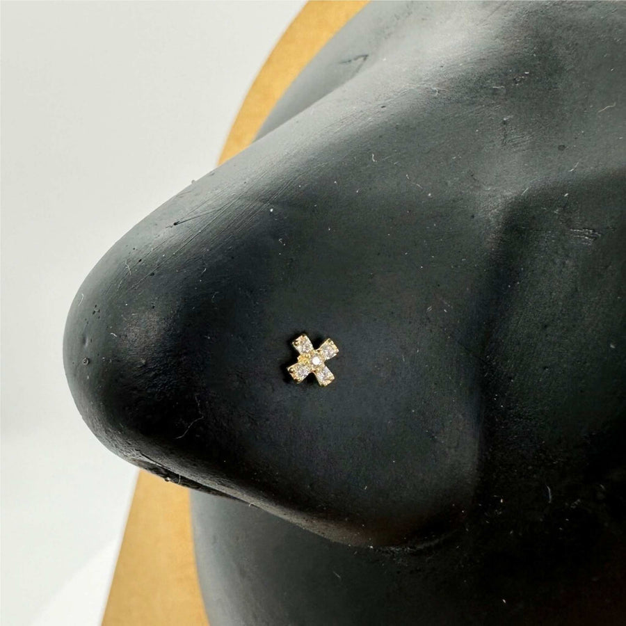 Sparkling X-shaped gold nose stud with cubic zirconia stones displayed on a nose model