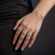 Three gold crown cubic zirconia rings worn on a hand against dark background.
