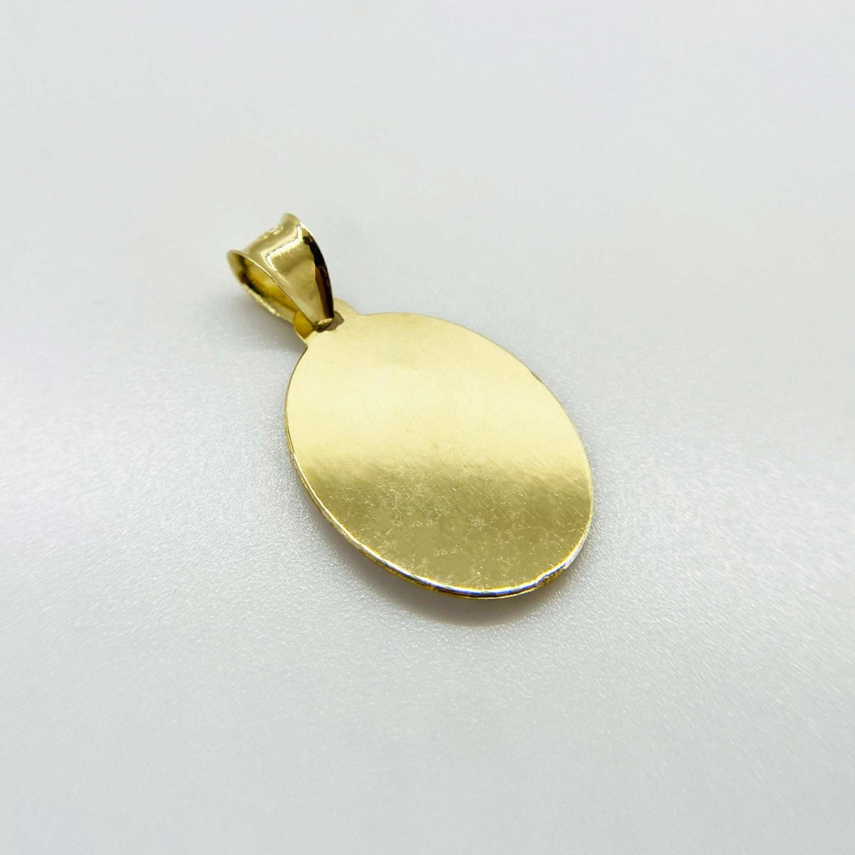 Reverse view of 14k gold oval Virgin Mary pendant displaying a plain brushed back surface