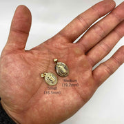 Small and medium gold Virgin Mary oval pendants held in palm with size labels.