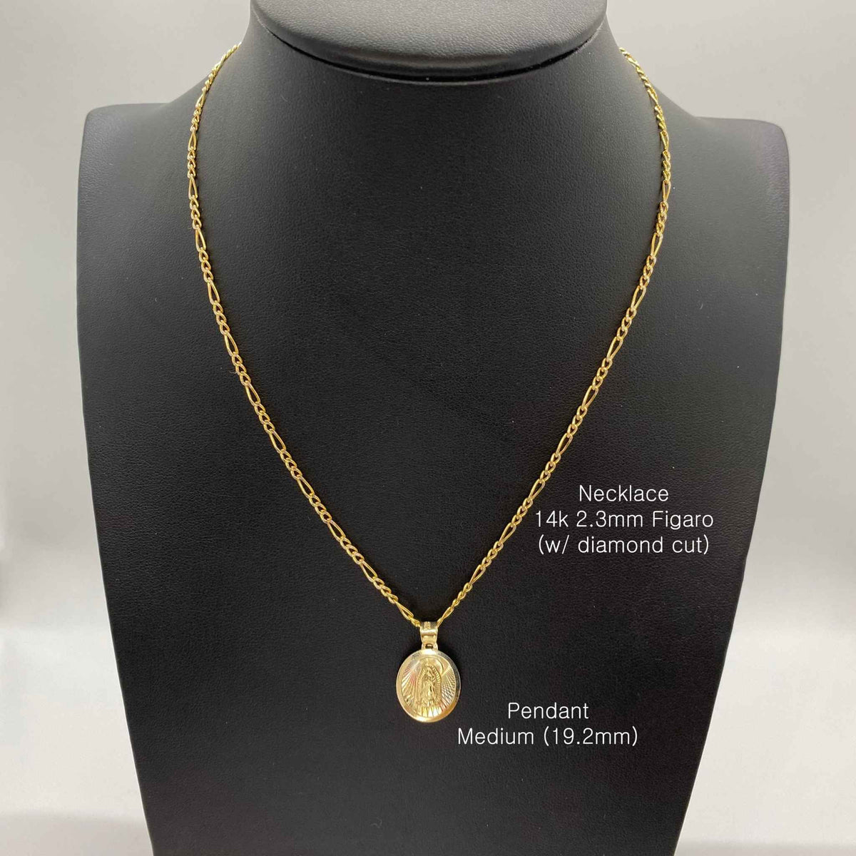 Medium gold Virgin Mary oval pendant necklace on figaro chain displayed on black bust.
