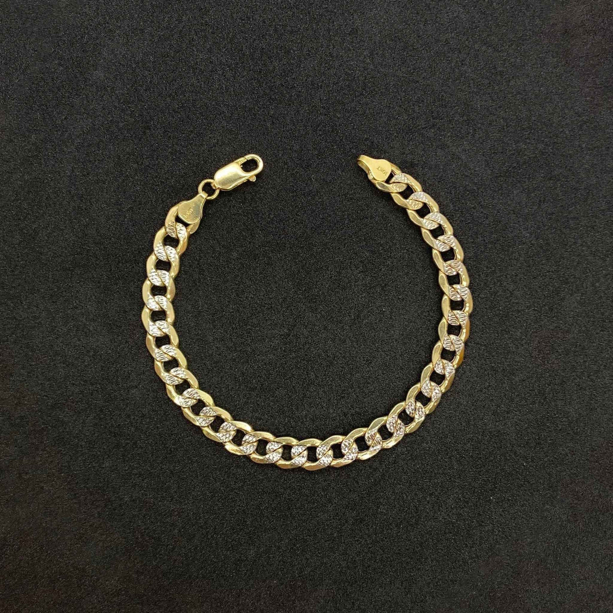 A 14k gold pave curb link bracelet with a lobster claw clasp on a dark background.