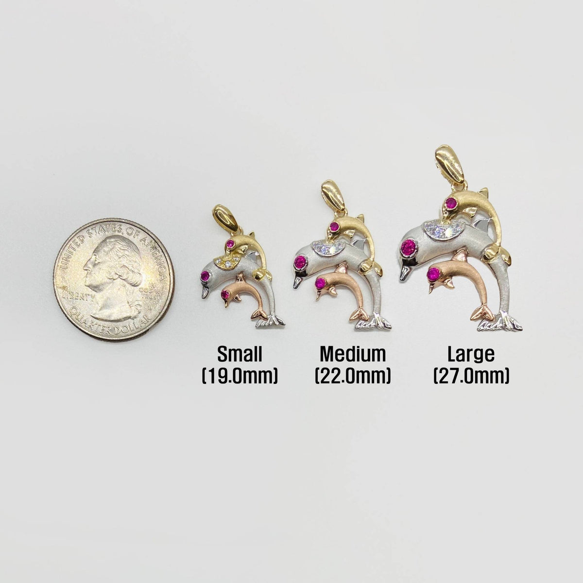 Three 14k tri-color gold trio dolphin CZ pendants shown next to a quarter for size scale.