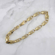 Textured 14k yellow gold Turkish link bracelet with a lobster clasp on marble.