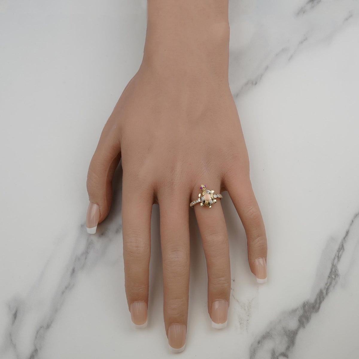 Gold turtle fancy ring with stone accents displayed on ring finger.
