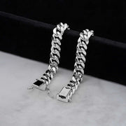 two thick 14k white gold cuban link bracelets displayed upright on a soft light colored surface