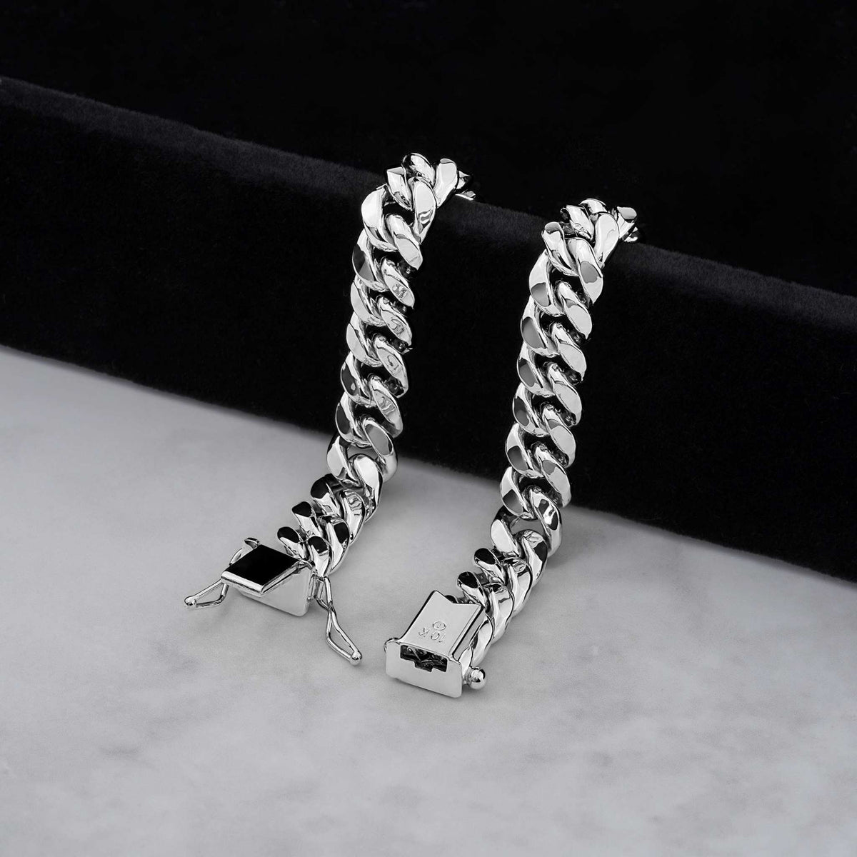 two thick 14k white gold cuban link bracelets displayed upright on a soft light colored surface