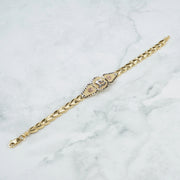 Tri-color gold chain bracelet displayed diagonally on a white and gray marble surface.