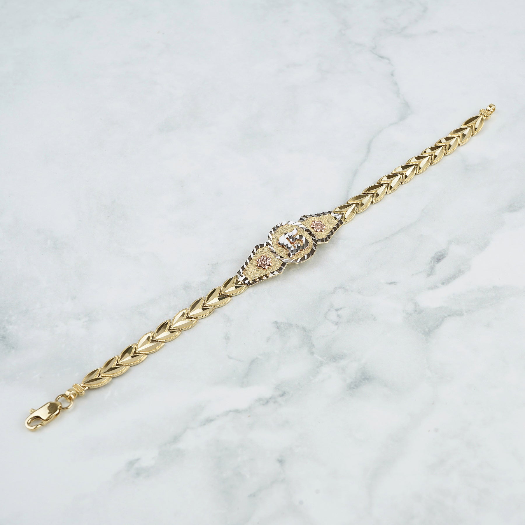 Tri-color gold chain bracelet displayed diagonally on a white and gray marble surface.