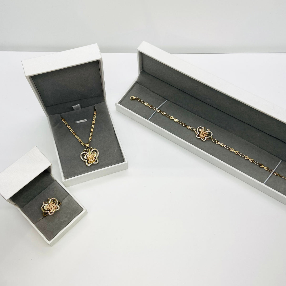 10k - 14k Gold butterfly necklace and bracelet in open jewelry boxes on a white background