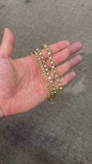 Person holding four different width 10k gold Alexander chain bracelets in palm