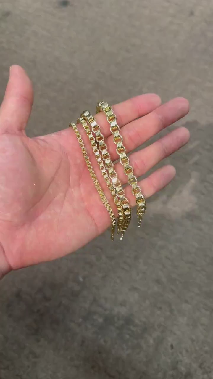 Person holding four different width 10k gold Alexander chain bracelets in palm