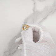 Gloved hand holding a tricolor gold Quinceañera ring with number 15 up close.