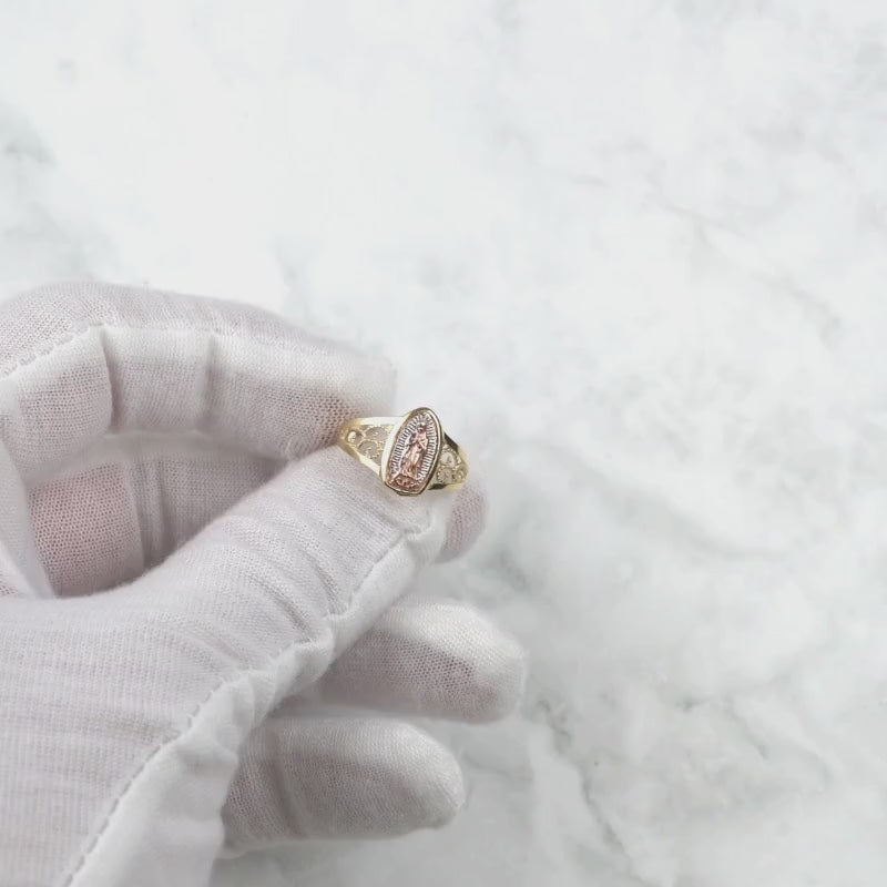 Gloved hand holding and rotating the 10k and 14k gold Alvia Virgin Mary ring.