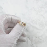 Gloved hand holding the tricolor gold lucky motif ring against a light background.