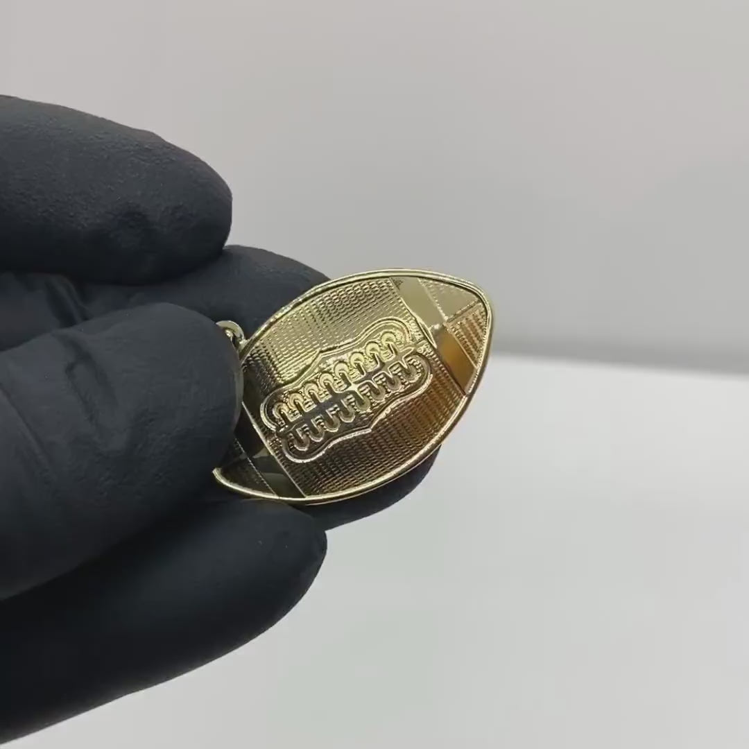 Gloved hand holding a polished 10k solid yellow gold American football pendant.