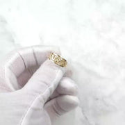 Gloved hand holding up the polished yellow gold lucky motif ring.